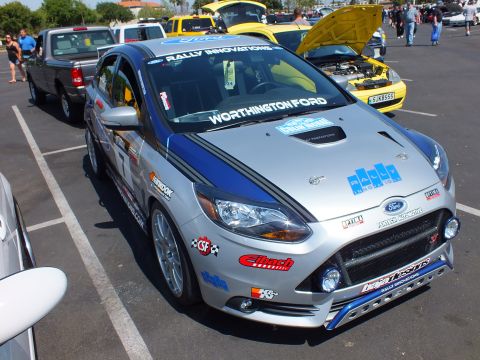 2003 Ford Crown Victoria - silver Ford Focus ST hatchback built as a rally car, plastered with sponsor decals reading Worthington Ford and Rally Innovations.