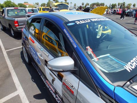 2003 Ford Crown Victoria - Side view of a blue-and-silver Ford Focus rally hatchback covered in sponsor decals including Ford, Roadwire, and Rally Innovations.