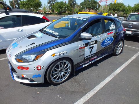 2003 Ford Crown Victoria - Front three-quarter view of a silver-and-blue Ford Focus ST race car with number 7 and multiple sponsor decals parked at a car meet.