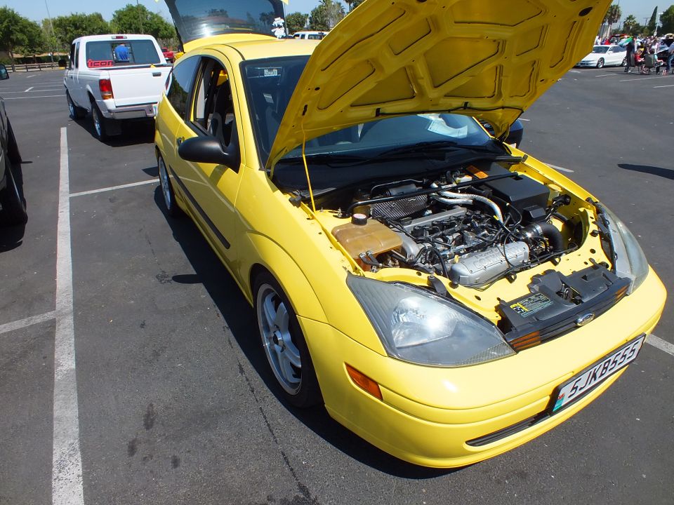 Yellow Ford Focus coupe with hood open showing engine bay