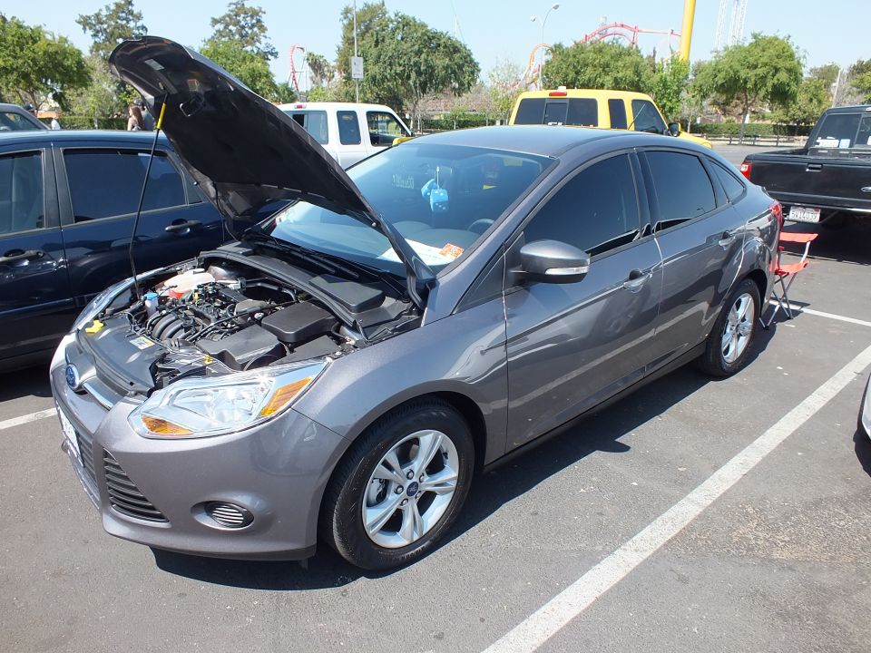 Gray Ford Focus sedan with raised hood at outdoor car show