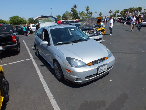 2003 Ford Crown Victoria - silver Ford Focus hatchback with its rear hatch raised, parked among other cars at a sunny outdoor show.