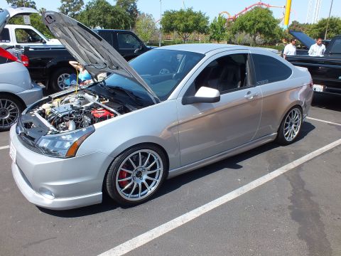 2003 Ford Crown Victoria - lowered silver Ford Focus coupe with its hood open and polished silver wheels, parked at an outdoor meet.