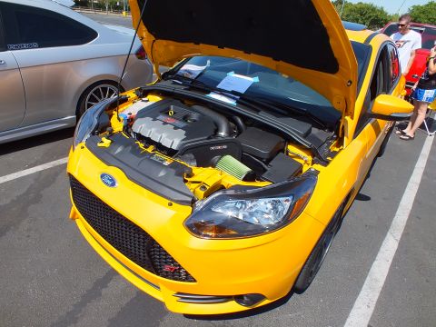 2003 Ford Crown Victoria - Front three-quarter view of a yellow Ford Focus with hood raised, displaying the engine bay at a car show.