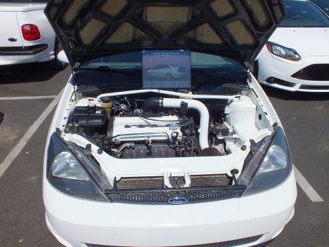 2003 Ford Crown Victoria - Front view of a white Ford Focus with hood raised, engine bay detailed in white with an info placard above it.