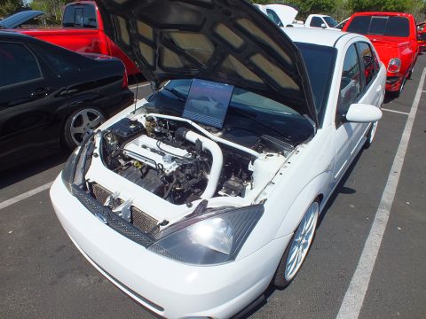 2003 Ford Crown Victoria - white Ford Focus sedan with hood raised, showing a detailed engine bay and an info placard, on silver wheels.