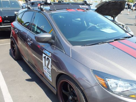 2003 Ford Crown Victoria - Side view of a gray Ford Focus hatchback with a red stripe, roof rack, and a number 12 racing decal on the door.