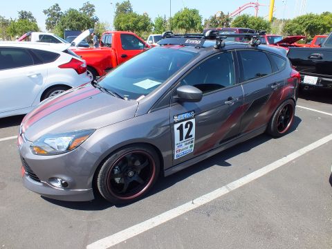 2003 Ford Crown Victoria - gray Ford Focus hatchback with red side graphics, roof rack, and a number 12 decal parked at a car meet.