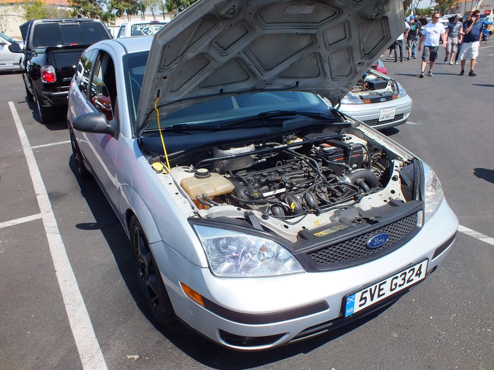 Silver Ford Focus sedan with hood open showing engine bay at a car show