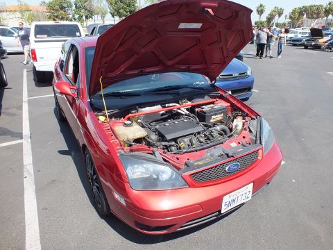 2003 Ford Crown Victoria - maroon Ford Focus sedan with black wheels sits with its hood open, revealing the engine bay in a parking lot.