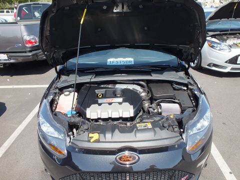 2003 Ford Crown Victoria - Close front view into a dark Ford Focus engine bay showing an ST-branded engine cover and yellow prop rod.