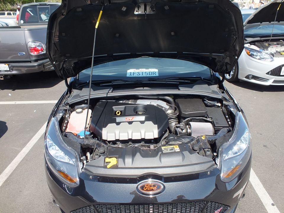 Front engine bay of a dark Ford Focus ST with hood open, ST cover visible