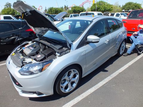 2003 Ford Crown Victoria - silver Ford Focus ST hatchback sits with its hood up showing the engine, coaster visible behind the lot.
