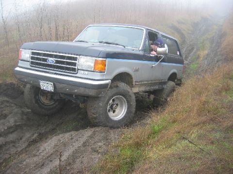 1989 Ford Bronco - This 1987 Ford Bronco navigates a muddy off-road trail, demonstrating its capability in challenging terrain.
