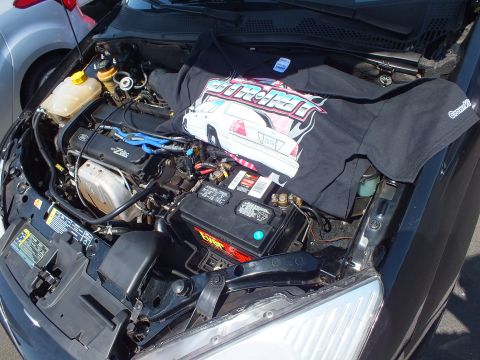 2003 Ford Crown Victoria - Close view of a car engine bay showing a Zetec engine, battery, and a printed black T-shirt draped over it.