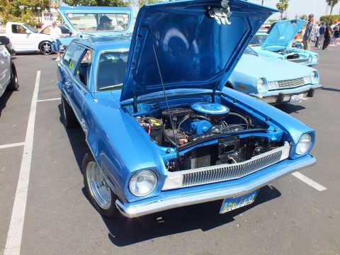 2003 Ford Crown Victoria - blue Ford Pinto with chrome bumpers and hood raised displays its engine bay at a sunny outdoor car show.