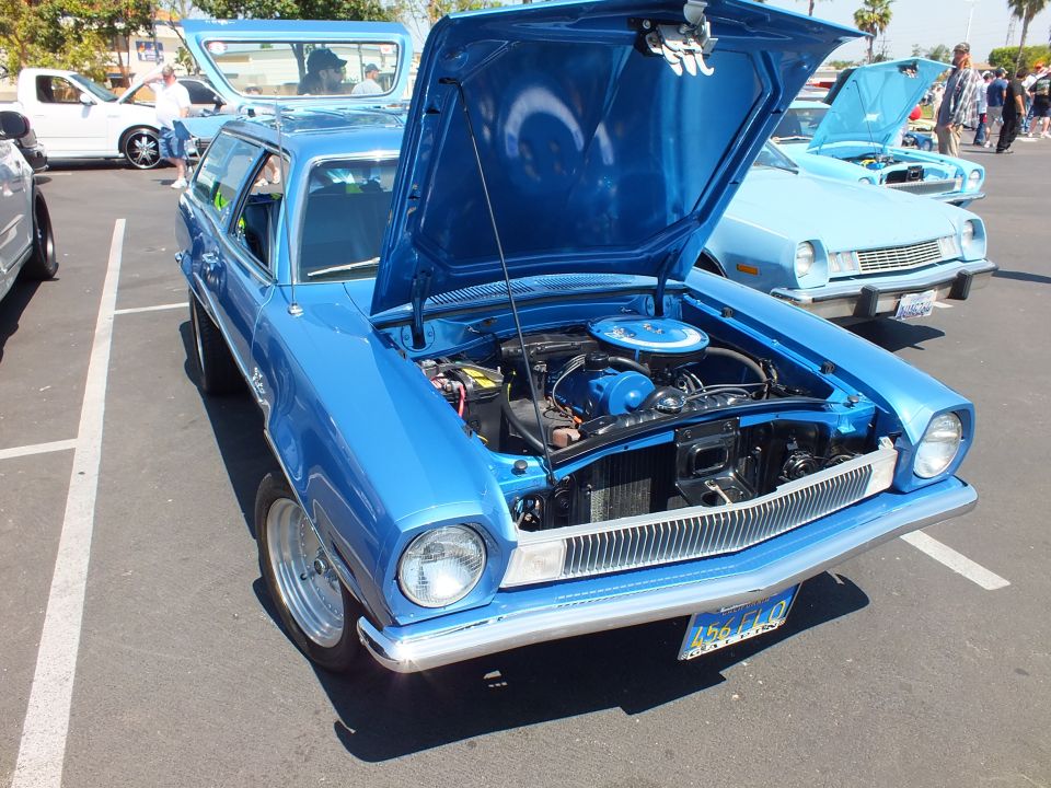 Blue Ford Pinto hatchback with hood open showing engine at car show