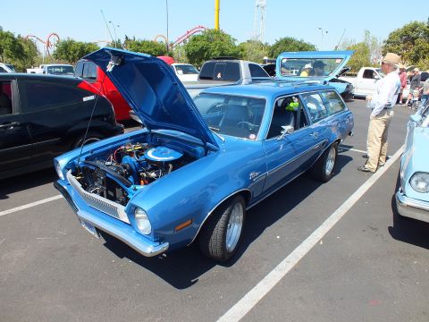 2003 Ford Crown Victoria - blue Ford Pinto station wagon sits with its hood open showing the engine, an amusement coaster behind the lot.