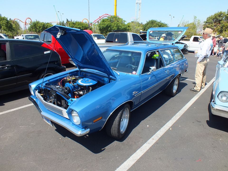 Blue Ford Pinto wagon with hood up at a car show, coaster in background