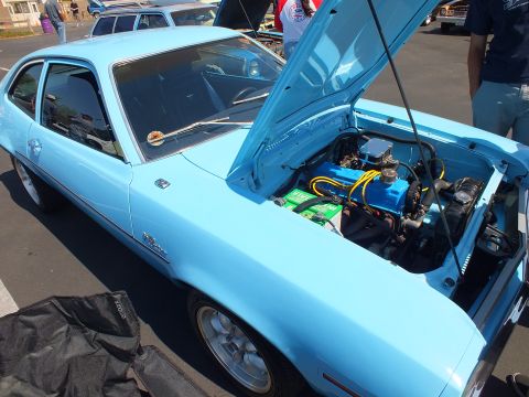 2003 Ford Crown Victoria - light blue Ford Pinto has its hood raised, revealing the engine bay with a blue valve cover, at a car show.