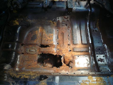 1975 Ford Ranchero - The interior floor pan of a vehicle shows extensive rust and deterioration.