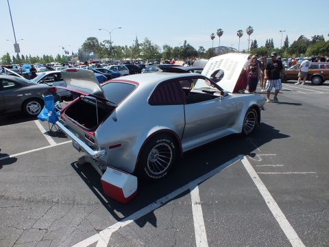 2003 Ford Crown Victoria - heavily modified silver hatchback shows its rear three-quarter with the hatch open, fat rear tires and flared bodywork at a car show.