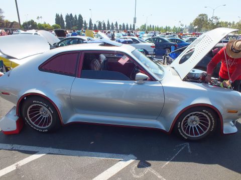 2003 Ford Crown Victoria - custom silver hatchback in profile shows wide fender flares, red accent trim and BFGoodrich-shod slotted wheels with the hood raised.