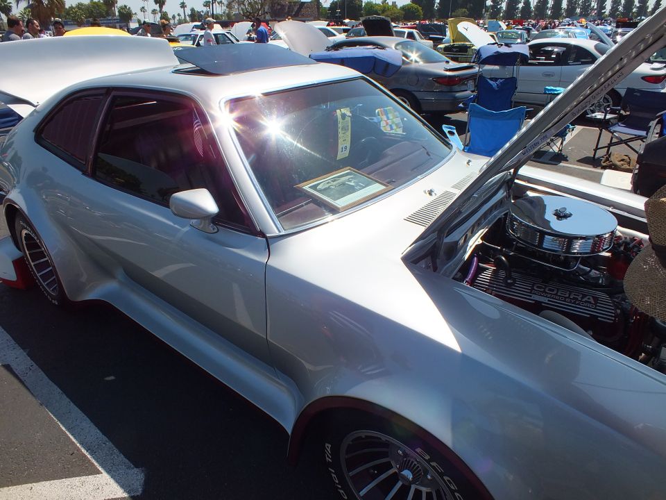 Silver custom car with Cobra valve-cover engine exposed, wide flares, red interior