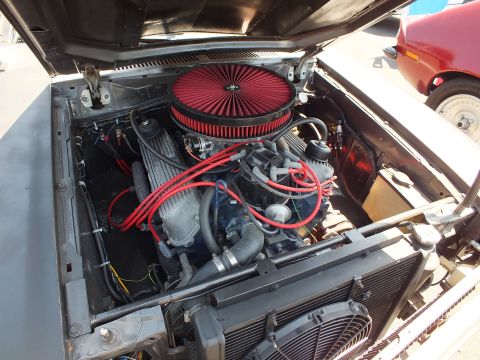 2003 Ford Crown Victoria - open engine bay shows a blue V8 topped with a red round air filter, red plug wires and an electric cooling fan.