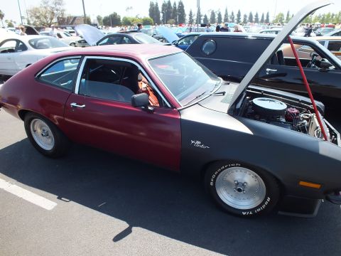 2003 Ford Crown Victoria - two-tone maroon-and-gray Ford Pinto hatchback shown in profile has its hood raised, riding on white slotted wheels with BFGoodrich tires.
