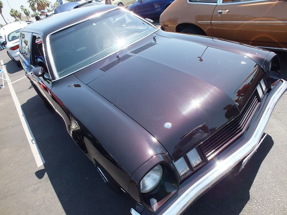 Dark maroon coupe high-angle front three-quarter, chrome bumper, hood louvers