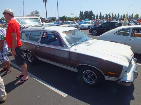 2003 Ford Crown Victoria - brown-and-white faux-wood Ford station wagon is shown front three-quarter with chrome mag wheels as a man in a red shirt stands by.