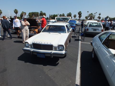 2003 Ford Crown Victoria - white Mercury-badged Bobcat station wagon with faux wood sides is shown head-on at a crowded outdoor car show.