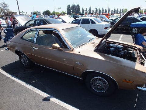 2003 Ford Crown Victoria - brown vintage two-door hatchback with wire-spoke wheels and its hood raised at an outdoor car show.