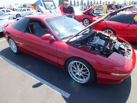 2003 Ford Crown Victoria - red sports coupe with polished multi-spoke wheels and its hood raised exposing the engine bay at a car show.