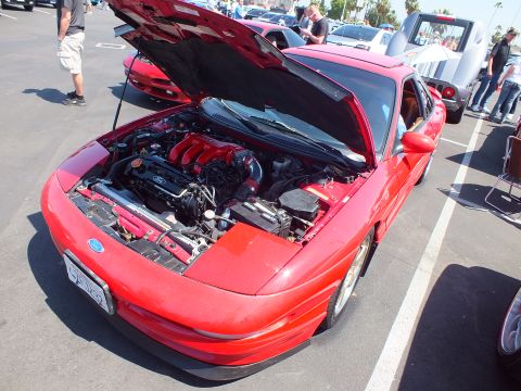 2003 Ford Crown Victoria - red sports coupe displayed front three-quarter with its hood raised exposing the engine at an outdoor car show.