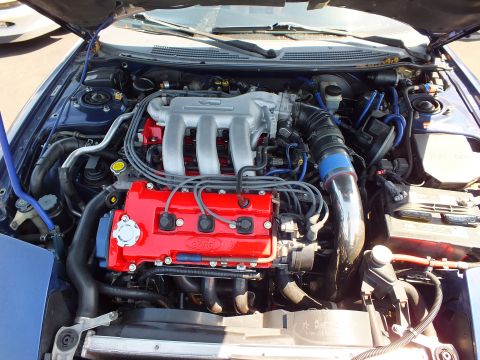 2003 Ford Crown Victoria - Engine bay of a blue car showing a red-finished valve cover marked Ford with polished intake and blue wiring.