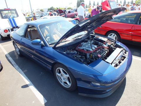 2003 Ford Crown Victoria - blue sports coupe with raised hood and tan interior parked at an outdoor car show among other coupes.