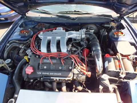 2003 Ford Crown Victoria - Close-up of an engine bay showing a Mazda V6 DOHC 24-valve engine with red spark plug wires.
