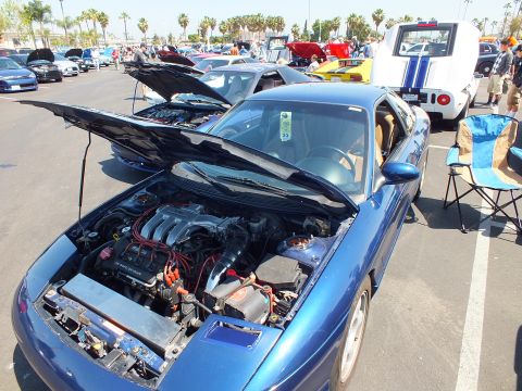 2003 Ford Crown Victoria - blue sports coupe with its hood raised exposing the engine bay, parked among rows of cars at a show.