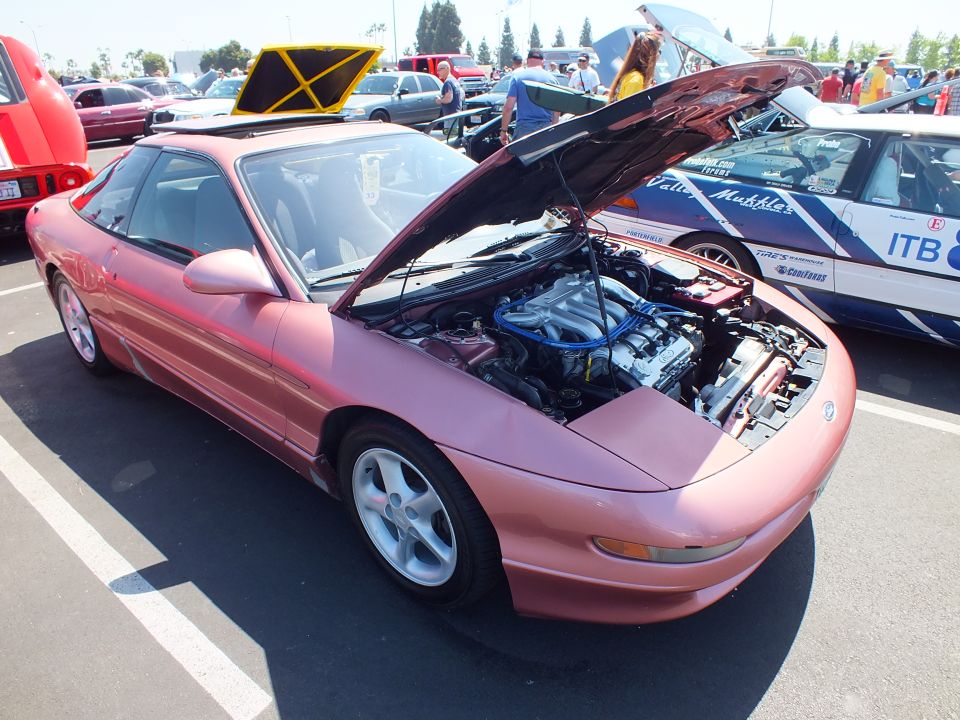 Salmon coupe with hood up showing blue valve covers at car show