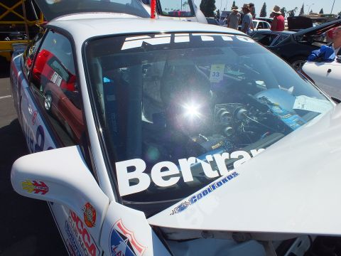 2003 Ford Crown Victoria - Close view through a white race car's windshield lettered 'Bertran' with a number 33 placard and bright sun glare.