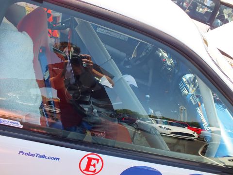 2003 Ford Crown Victoria - photographer is reflected in a white car's side window bearing a 'ProbeTalk.com' decal at an outdoor show.