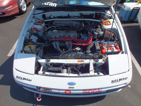 2003 Ford Crown Victoria - open front engine bay of a white show car reveals a four-cylinder motor with red plug wires and Auto Meter decals.