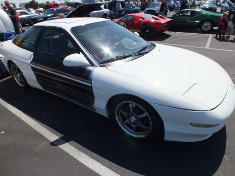 2003 Ford Crown Victoria - white sports coupe with a black lower side panel and chrome multi-spoke wheels is parked at an outdoor car show.