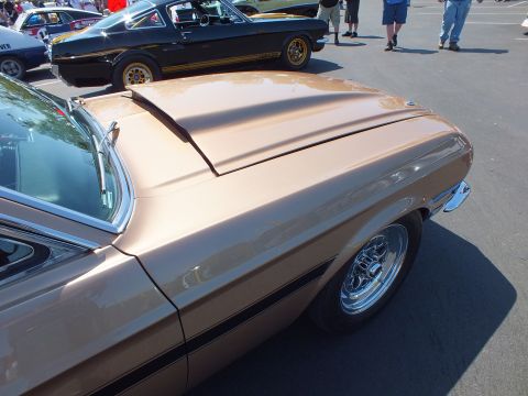 2003 Ford Crown Victoria - gold rear quarter and trunk of a classic Mustang are in front of a black-and-gold fastback at the show.