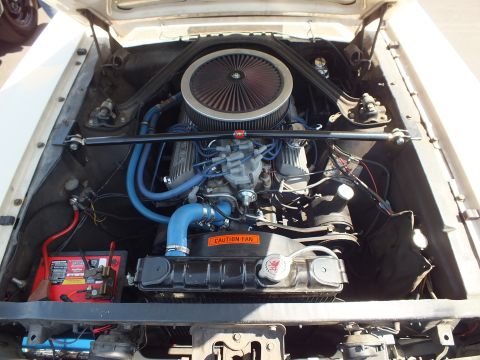 2003 Ford Crown Victoria - detailed V8 engine bay shows a chrome air cleaner, blue spark plug wires, a red battery and a Caution Fan warning label.