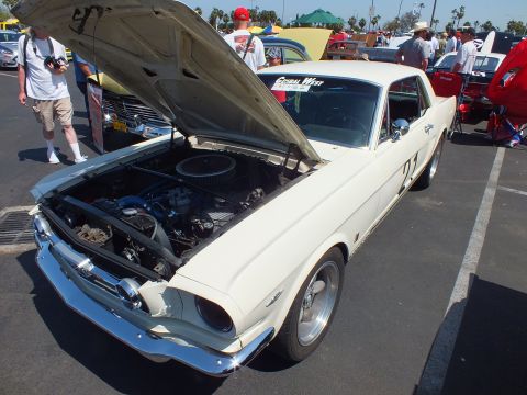 2003 Ford Crown Victoria - white vintage coupe wearing race number 22 sits with hood raised among other cars at a sunny outdoor show.