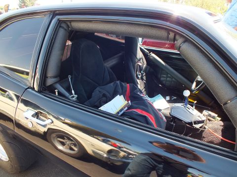 2003 Ford Crown Victoria - Through an open window, a black car reveals a black racing seat, roll cage and assorted gear inside its stripped cabin.