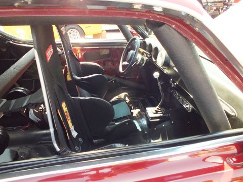 2003 Ford Crown Victoria - Through the window, a red race car shows a black racing bucket seat, roll cage, harness and small racing steering wheel.